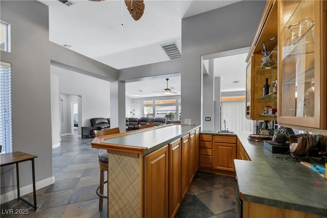 kitchen with kitchen peninsula, ceiling fan, and a breakfast bar area