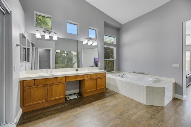 bathroom with hardwood / wood-style flooring, vanity, lofted ceiling, and independent shower and bath