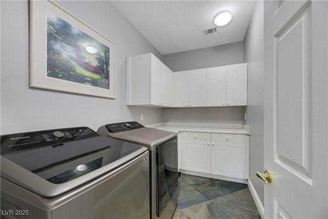 clothes washing area featuring cabinets and washing machine and clothes dryer