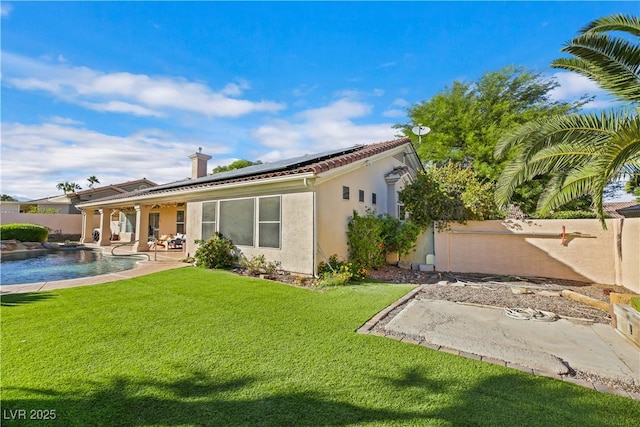 back of property featuring solar panels, a fenced in pool, a yard, and a patio