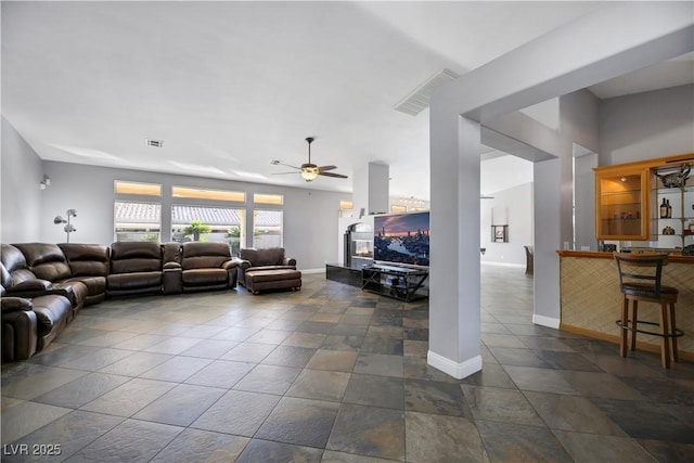 living room featuring bar area, ceiling fan, and a fireplace