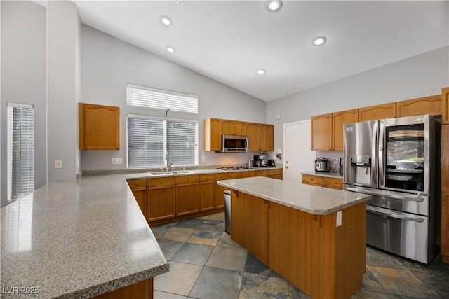 kitchen with a breakfast bar, stainless steel appliances, sink, high vaulted ceiling, and a center island