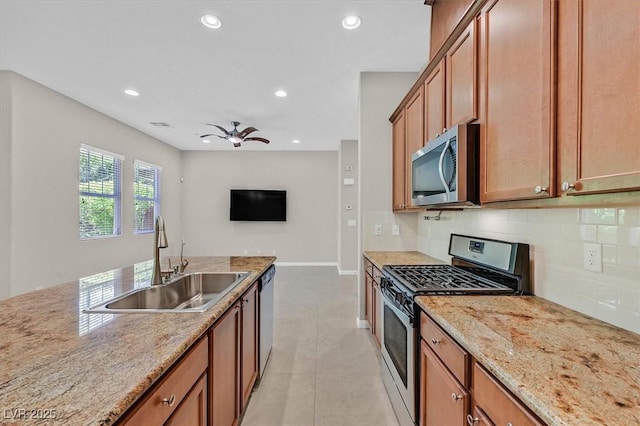 kitchen featuring light stone countertops, stainless steel appliances, ceiling fan, sink, and light tile patterned floors