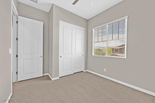 unfurnished bedroom with light colored carpet, a closet, and ceiling fan