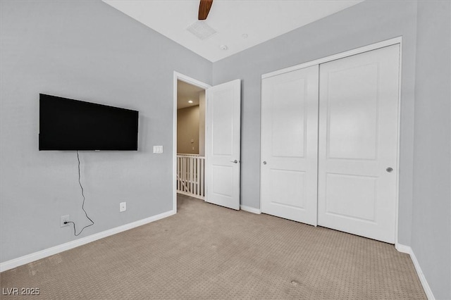 unfurnished bedroom featuring ceiling fan, light colored carpet, and a closet