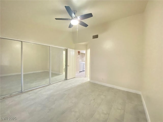 unfurnished bedroom with ceiling fan, light tile patterned floors, a towering ceiling, washer / clothes dryer, and a closet