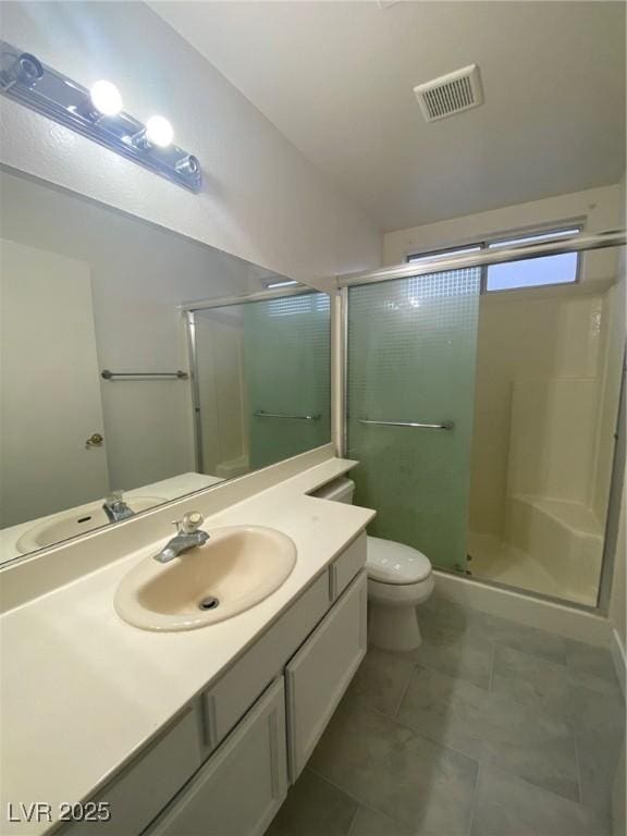 bathroom featuring tile patterned floors, vanity, toilet, and a shower with shower door