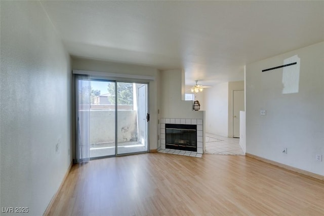 unfurnished living room with ceiling fan, a fireplace, and light wood-type flooring