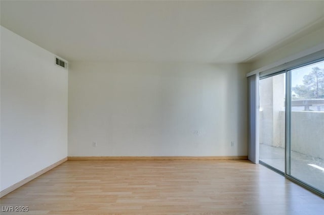 empty room featuring light wood-type flooring, visible vents, and baseboards