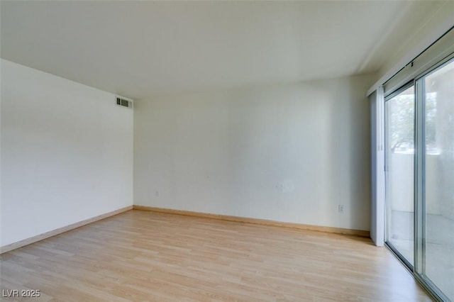 unfurnished room featuring light wood-style floors, visible vents, and baseboards