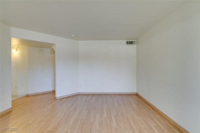 empty room featuring light wood-type flooring, visible vents, and baseboards