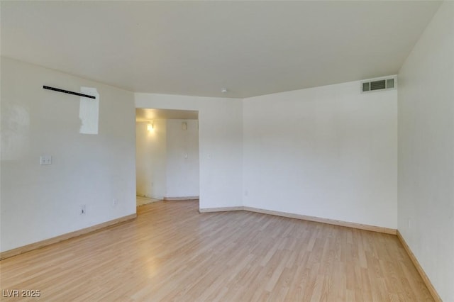 unfurnished room featuring light wood-type flooring, baseboards, and visible vents