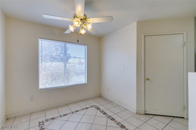 empty room with light tile patterned flooring, a ceiling fan, and baseboards