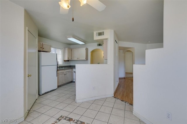 kitchen featuring light tile patterned floors, visible vents, freestanding refrigerator, ceiling fan, and a sink