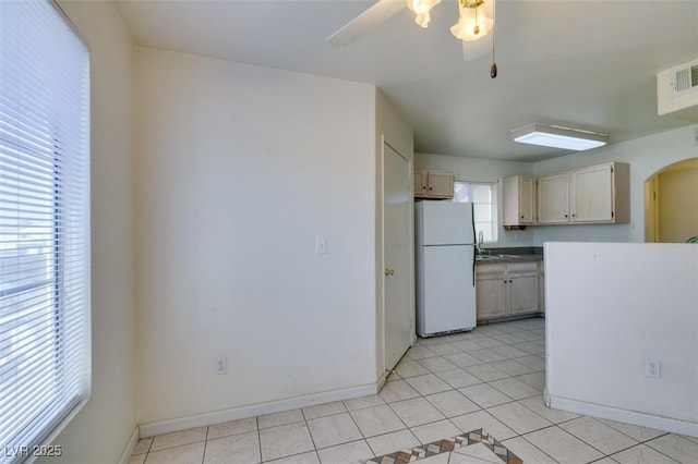 kitchen with arched walkways, ceiling fan, light tile patterned flooring, and freestanding refrigerator