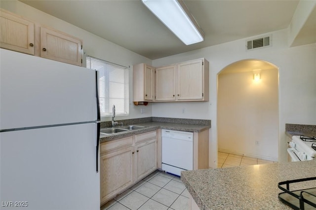 kitchen with arched walkways, visible vents, light tile patterned flooring, a sink, and white appliances