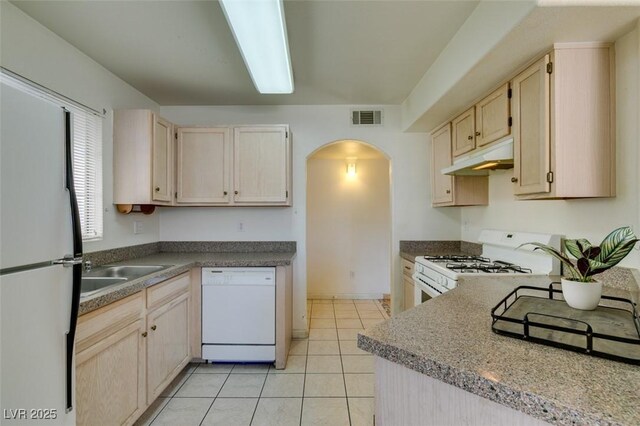 kitchen featuring light brown cabinetry, light tile patterned flooring, white appliances, and sink