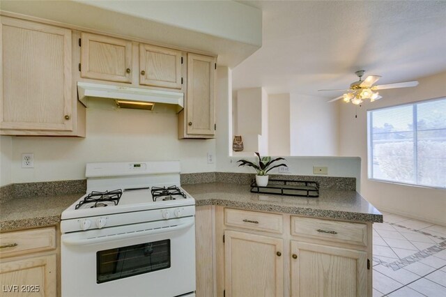 kitchen with ceiling fan, light brown cabinetry, light tile patterned floors, and white gas range oven