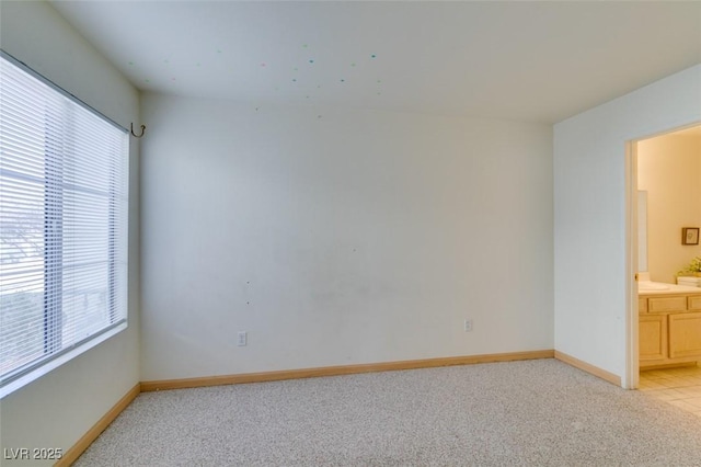 unfurnished room featuring light colored carpet and baseboards