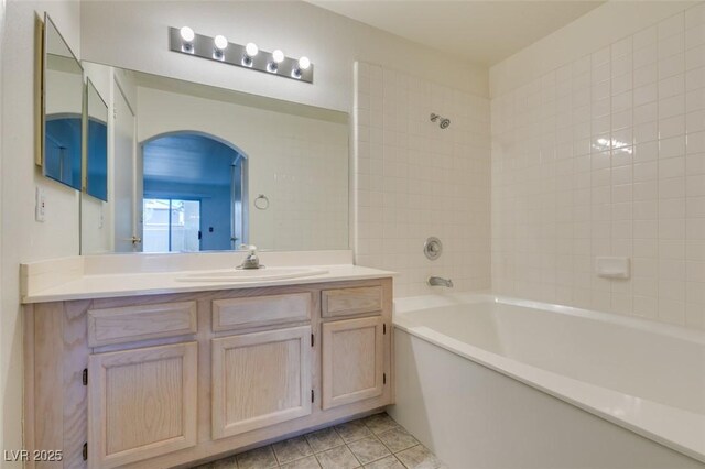 bathroom with tile patterned floors, vanity, and tiled shower / bath