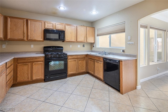 kitchen with black appliances, light tile patterned floors, and sink