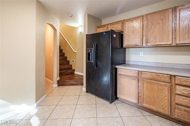 kitchen featuring light tile patterned floors and black refrigerator with ice dispenser