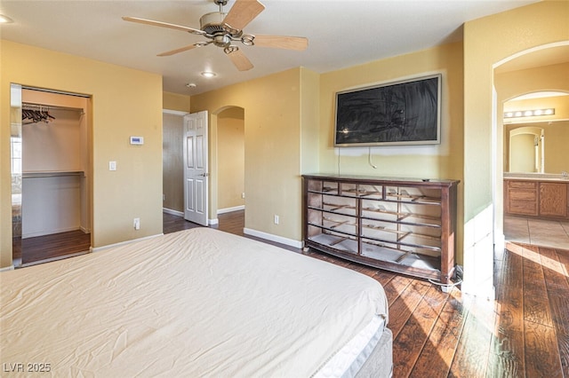 bedroom with a walk in closet, ceiling fan, connected bathroom, dark hardwood / wood-style floors, and a closet