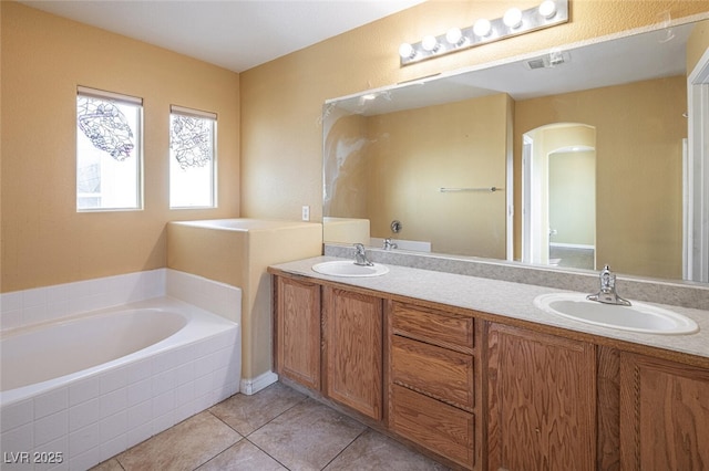 bathroom with tile patterned floors, vanity, and tiled bath