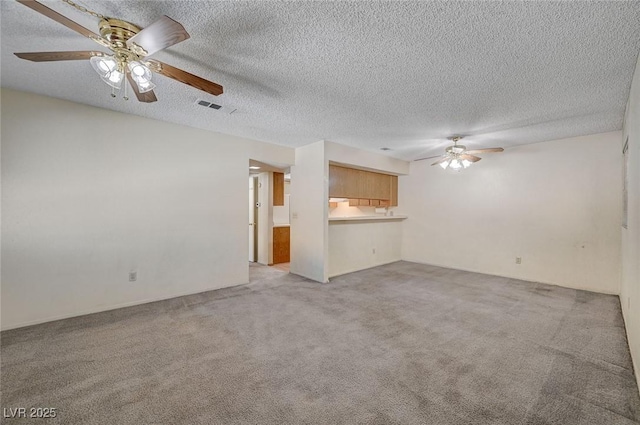 unfurnished living room with a textured ceiling, ceiling fan, and light carpet