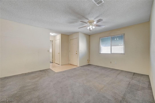 carpeted spare room featuring a textured ceiling and ceiling fan