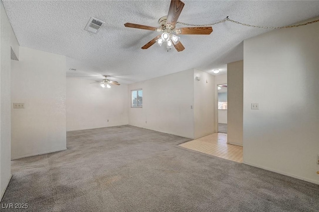 carpeted empty room with ceiling fan and a textured ceiling