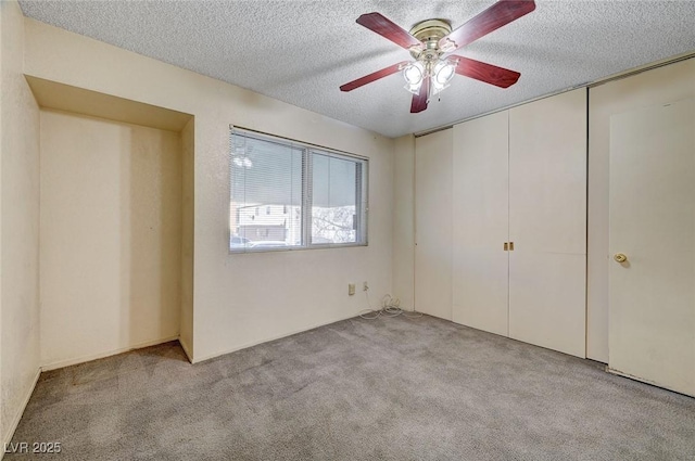 unfurnished bedroom with ceiling fan, light colored carpet, and a textured ceiling