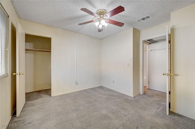 unfurnished bedroom featuring ceiling fan, light colored carpet, a textured ceiling, and a closet