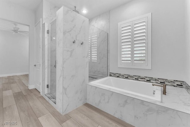 bathroom featuring ceiling fan, hardwood / wood-style floors, and plus walk in shower