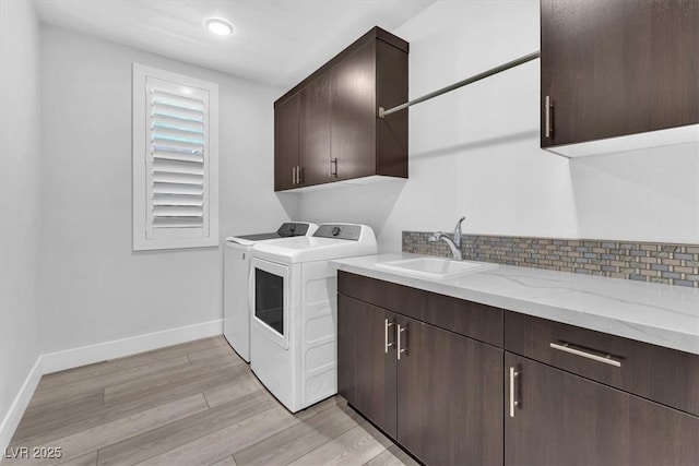 laundry area with sink, light hardwood / wood-style floors, cabinets, and washer and dryer