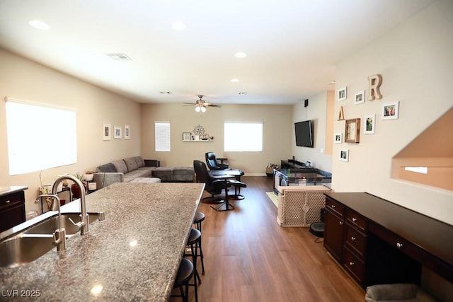 kitchen featuring ceiling fan, sink, dark hardwood / wood-style floors, a breakfast bar, and dark brown cabinets