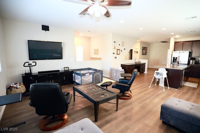 living room with light wood-type flooring, ceiling fan, and sink