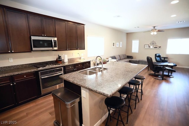 kitchen featuring sink, dark hardwood / wood-style floors, a kitchen bar, a kitchen island with sink, and appliances with stainless steel finishes