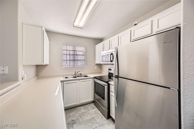 kitchen with white cabinetry, sink, light tile patterned floors, and stainless steel appliances