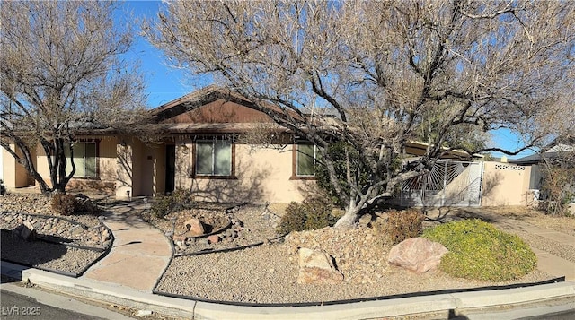 view of front of house with stucco siding and a gate