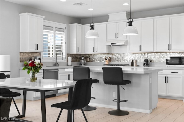 kitchen with dishwashing machine, hanging light fixtures, backsplash, white cabinets, and a kitchen island