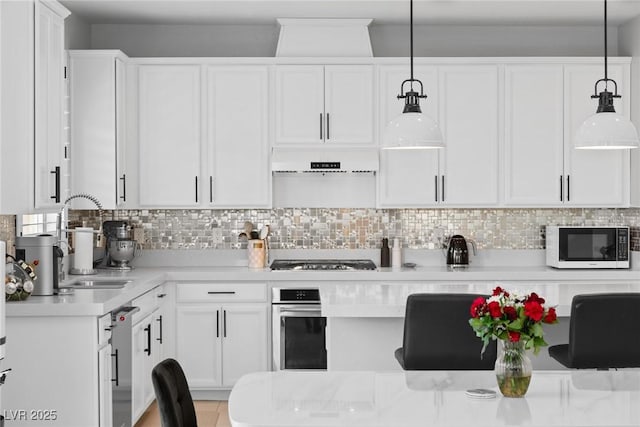 kitchen with white cabinets, sink, tasteful backsplash, decorative light fixtures, and stainless steel appliances