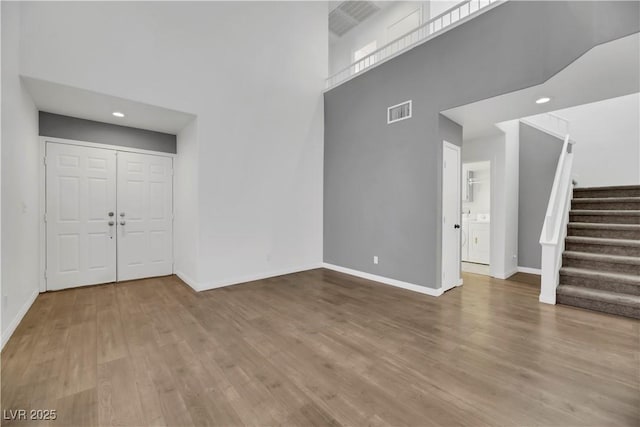 foyer entrance featuring a towering ceiling and wood-type flooring