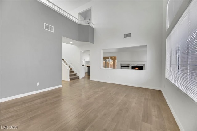 unfurnished living room featuring a towering ceiling and wood-type flooring