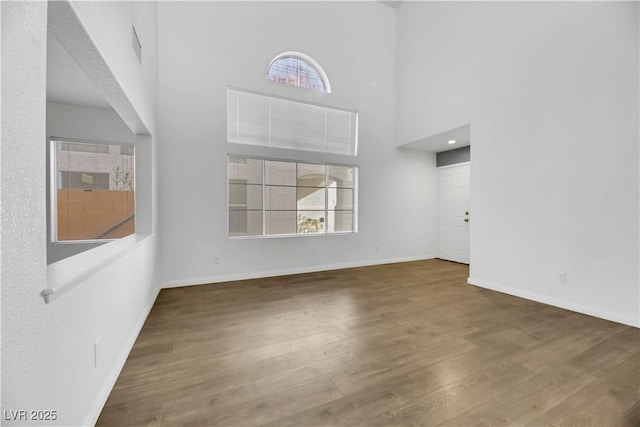 unfurnished living room featuring dark hardwood / wood-style flooring, plenty of natural light, and a high ceiling