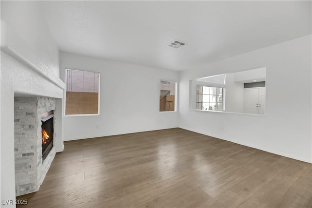 unfurnished living room featuring a stone fireplace and dark hardwood / wood-style floors