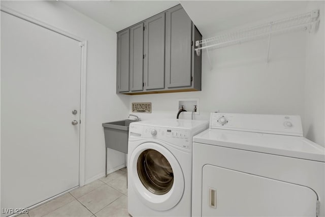 laundry area featuring cabinets, light tile patterned floors, washing machine and dryer, and sink