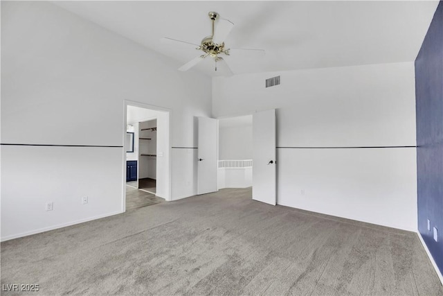 unfurnished bedroom with ensuite bath, ceiling fan, high vaulted ceiling, and light carpet