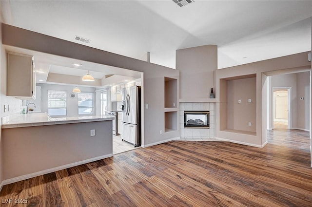 unfurnished living room with built in shelves, a fireplace, and hardwood / wood-style flooring