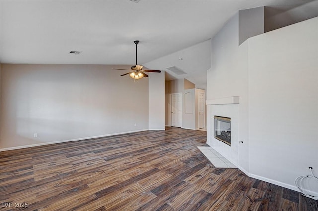 unfurnished living room featuring a tiled fireplace, ceiling fan, dark wood-type flooring, and lofted ceiling